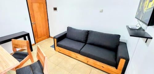 un sofá negro en una sala de estar con TV en Belgrano 555 en San Martín de los Andes