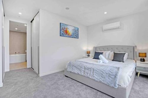 a white bedroom with a bed and a bathroom at 3 Bedrooms Apt in Glen Waverley central * parking in Glen Waverley