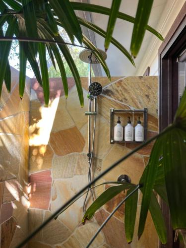 una ducha en una habitación con una pared de piedra en Away Guesthouse- Away on Shirley Lane, en Byron Bay