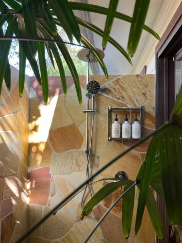 a shower in a room with a stone wall at Away Guesthouse- Away on Shirley Lane in Byron Bay