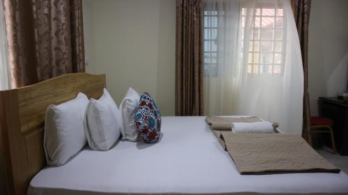 1 dormitorio con 1 cama con almohadas blancas en Crystal Premier Hotel, en Pantang