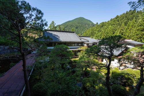 a building with trees in front of a mountain at Temple Lodging Shukubo Kakurinbo in Minobu