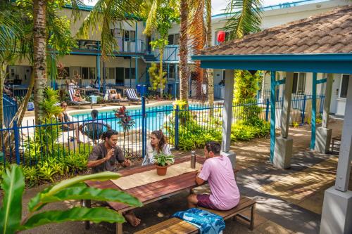 a group of people sitting at a picnic table by a pool at YHA Cairns Central in Cairns