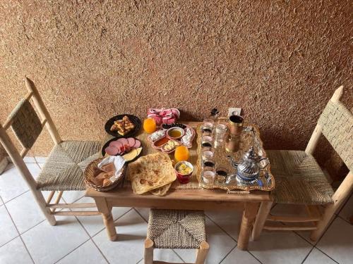 艾濟拉勒的住宿－Hôtel Chez MARZOUQ，一张桌子,上面有食物,还有两把椅子