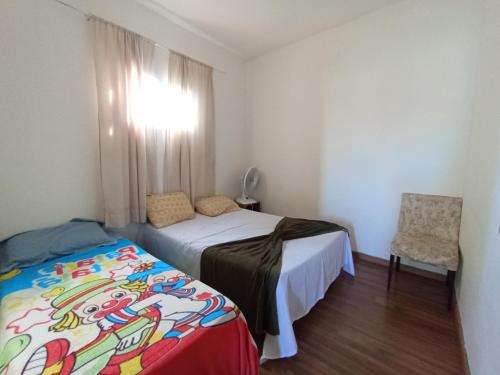 um quarto com uma cama, uma cadeira e uma janela em Casa pertinho da praia com piscina, wifi; em Vila Velha