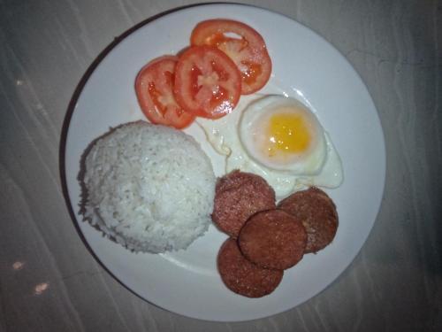 a plate of food with rice and an egg and tomatoes at Gratum Beach Resort in Dapitan