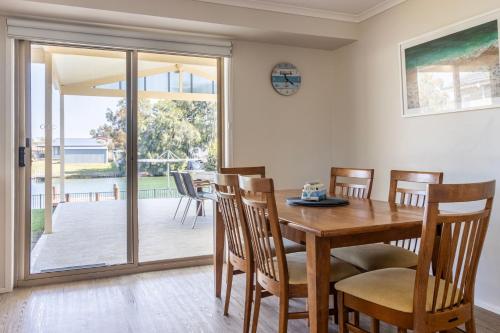 a dining room with a wooden table and chairs at Seabreeze on Ibis in Sussex inlet