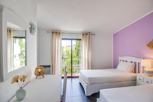 ein weißes Schlafzimmer mit 2 Betten und einem Fenster in der Unterkunft Seaside Retreat with Pool, AC, and Fast Wi-Fi in Albufeira
