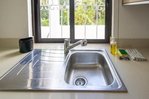 eine Edelstahlspüle in einer Küche mit Fenster in der Unterkunft Seaside Retreat with Pool, AC, and Fast Wi-Fi in Albufeira
