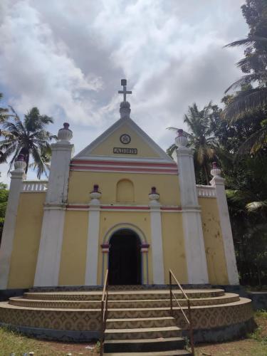 a yellow and white church with stairs in front at Bliss Homestay Munroe Island in Munroe Island