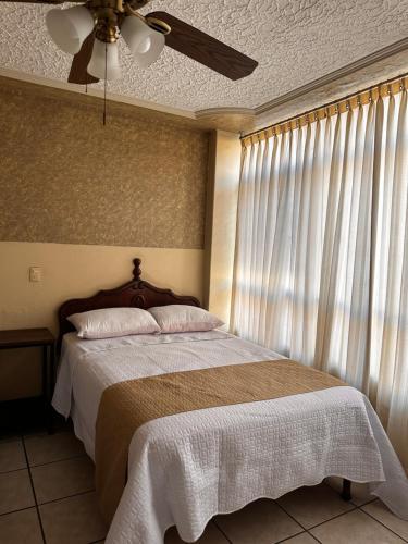a bedroom with a bed with a ceiling fan and a window at Hotel Palacio in San Juan de los Lagos