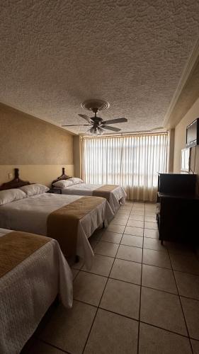 a hotel room with three beds and a ceiling fan at Hotel Palacio in San Juan de los Lagos