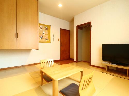 a living room with a table and chairs and a television at Pension Avenue in Yamanakako