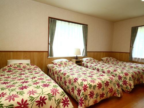 Pension Avenue في ياماناكاكو: سريرين في غرفة الفندق مع ورود
