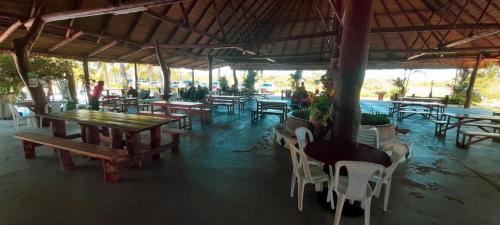 un restaurant avec des tables en bois ainsi que des chaises et des tables blanches dans l'établissement RIOPARK BEACH HOTEL, à Yopal