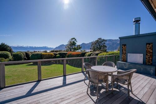 un patio con tavolo e sedie su un ponte di Hāwea Lakehouse - Lake Hāwea Holiday Home a Lake Hāwea