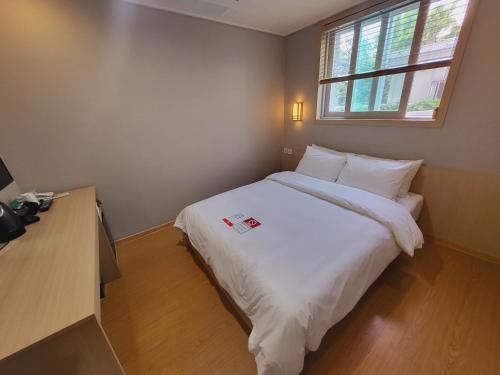 a bedroom with a white bed and a window at Hotel razaB in Pohang