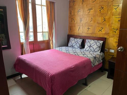 a bedroom with a bed with a pink blanket at Hotel las Nieves LD in Bogotá