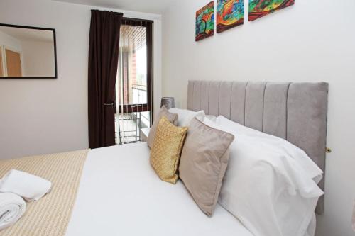 Schlafzimmer mit einem Bett mit weißer Bettwäsche und Kissen in der Unterkunft Autumn Heights Apartments in Telford