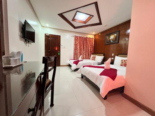 Cette chambre comprend deux lits et une télévision. dans l'établissement Mariafe Inn, à Puerto Princesa