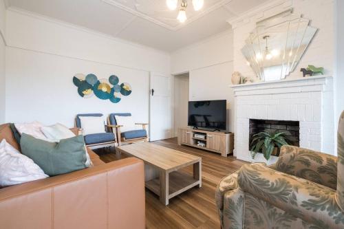 a living room with a couch and a fireplace at 'The Zophey House' A Charming Coastal Cottage in Rosebud
