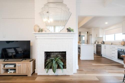 a living room with a white brick fireplace at 'The Zophey House' A Charming Coastal Cottage in Rosebud