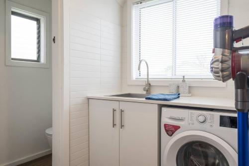 a kitchen with a washing machine and a sink at 'The Zophey House' A Charming Coastal Cottage in Rosebud