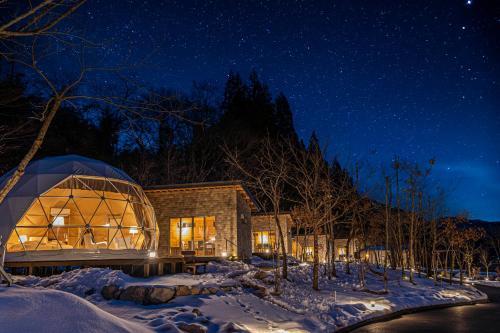 a glass house in the snow at night at mokki STARDUST GLAMPING in Achi