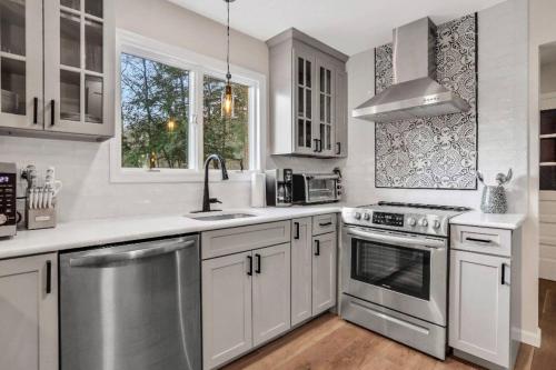 a kitchen with white cabinets and stainless steel appliances at 3 Bedroom Hilltop Escape with 5 Private Acres and Hot Tub in Marlboro