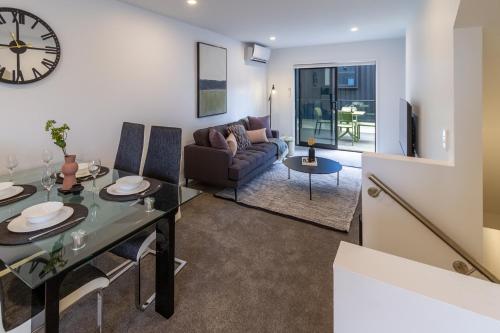 a living room with a table and a clock on the wall at Tuam Street Treasure- 2 Bed 2 Bath in Christchurch