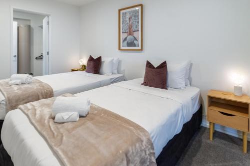 a bedroom with two beds with white sheets and a desk at Tuam Street Treasure- 2 Bed 2 Bath in Christchurch