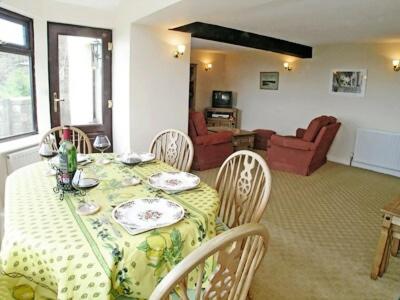 a dining room with a table and chairs with a green and white table cloth at Vale View Cottage in Cinderford