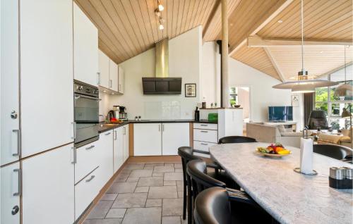 a kitchen with white cabinets and a table with chairs at Holiday Home Sivsangervej Ebeltoft Iii in Øksenmølle
