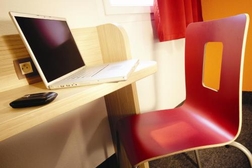 einen Laptop auf einem Schreibtisch mit einem roten Stuhl in der Unterkunft Première Classe Istres in Istres