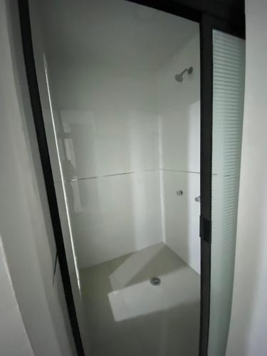 W łazience znajduje się biały prysznic ze szklanymi drzwiami. w obiekcie Tokyo Motel w mieście San Bernabé Amaxac de Guerrero