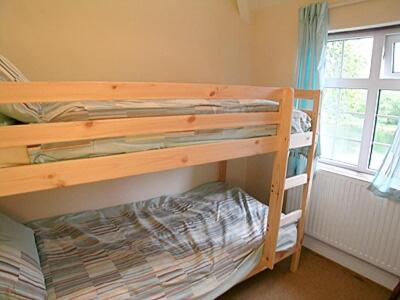 a bedroom with two bunk beds and a window at Tyn Y Graig Cottage in Crynant