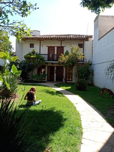 a woman sitting on the grass in front of a house at Rossco Hostel & Hotel in San Cristóbal de Las Casas