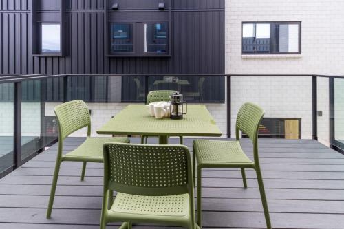 a green table and chairs on a balcony at Tuam Street Treasure- 2 Bed 2 Bath in Christchurch
