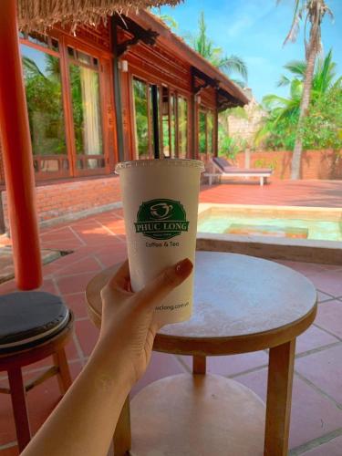 a person holding a cup of coffee on a table at Full Moon Village Resort in Mui Ne