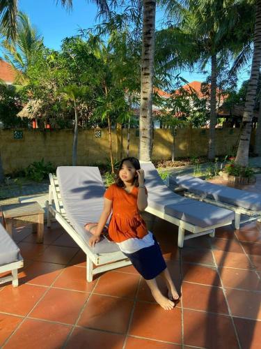 a young girl is sitting on a bed at Full Moon Village Resort in Mui Ne