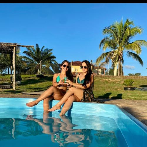 two women sitting next to a swimming pool at ESPACO LEÃO EVENTOS, Chácara para eventos, lazer ou descanso in Rio Branco