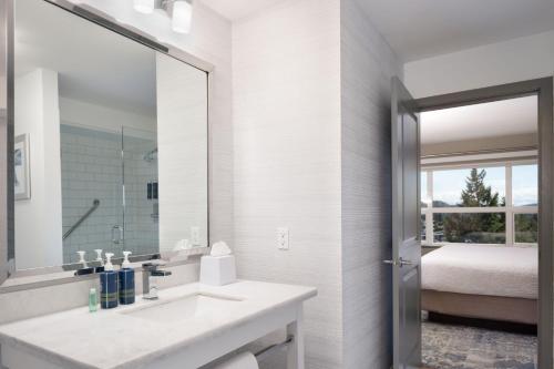 ein weißes Badezimmer mit einem Waschbecken und einem Spiegel in der Unterkunft Four Points by Sheraton Victoria Gateway in Victoria
