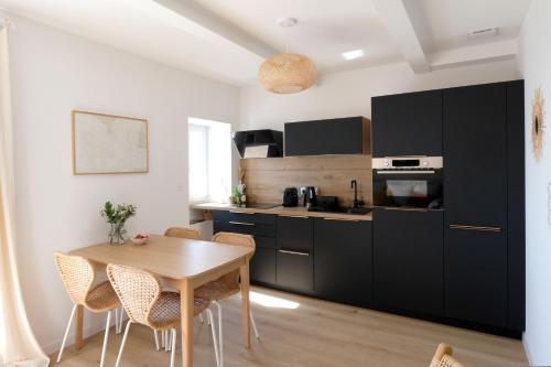 a kitchen with black cabinets and a wooden table at Appartement en front de mer avec vue imprenable sur la grande plage des Sables d'Olonne in Les Sables-dʼOlonne