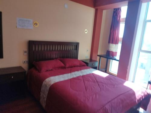 um quarto com uma cama grande e um cobertor vermelho em HOSTAL YOKOSO em Uyuni