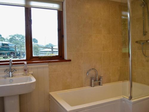a bathroom with a sink and a tub and a window at Little Shelvin Farm Cottage in Luppitt