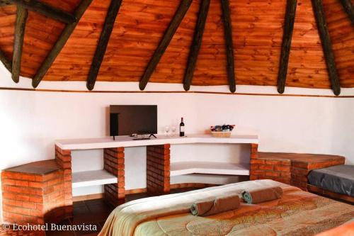 een kamer met een bureau, een televisie en een bed bij Ecohotel Buenavista in Villa de Leyva