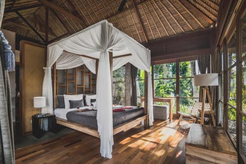 a bedroom with a bed with a canopy at Luwak Ubud Villa in Ubud
