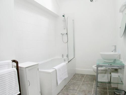 a white bathroom with a tub and a sink at Cow Shed in Farden