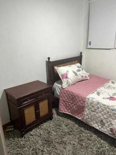 a bedroom with a bed and a night stand next to a table at APTO DOS ALCOBAS MESETA in Bucaramanga