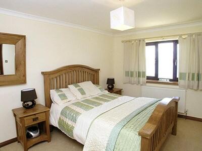a bedroom with a large bed and a window at Chestnut Cottage in Innellan
